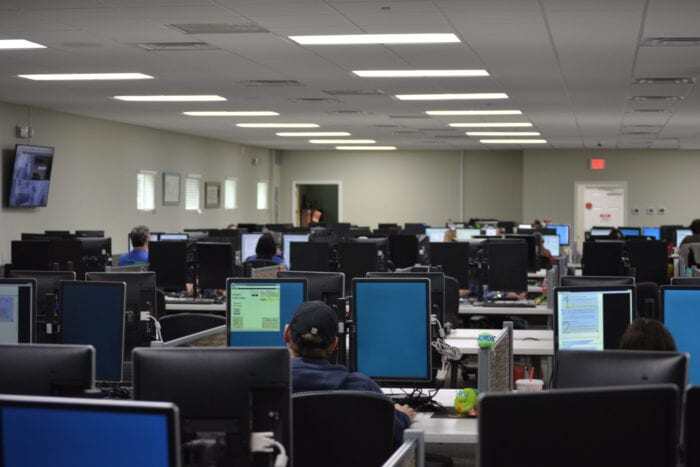 Braille Works staff working on accessible documents in front of a room full of monitors