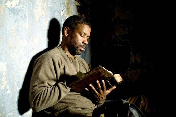Eli (Denzel Washington) sitting against a wall reading during a scene in the Book of Eli Eli (Denzel Washington) sitting against a wall reading during a scene in the Book of Eli
