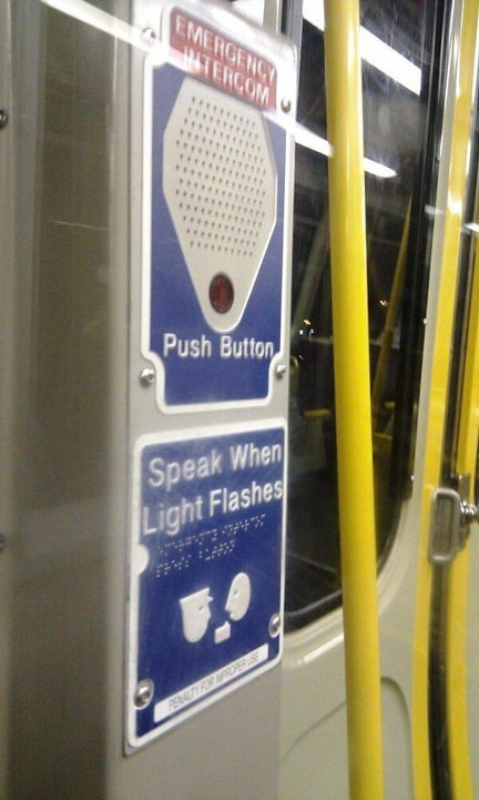 Subway emergency intercom with the phrase "speak when the light flashes" written in print and braille. Subway emergency intercom with the phrase "speak when the light flashes" written in print and braille.