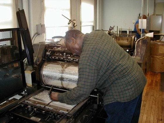 Image showing a man operating a braille press machine. Image showing a man operating a braille press machine.