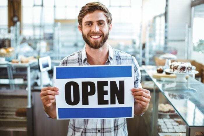 business owner holding "open" sign