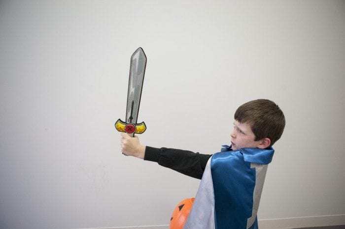 child in a superhero costume with a sword