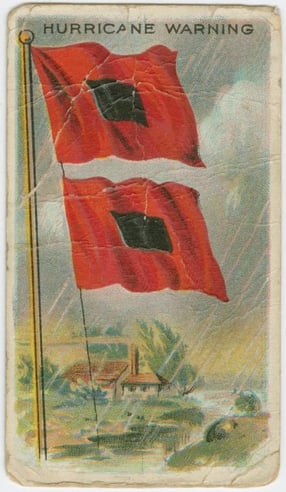 Universally recognized Hurricane Warning flags. Two red flags with black squares in the center and a beachfront home in the background. Universally recognized Hurricane Warning flags. Two red flags with black squares in the center and a beachfront home in the background.