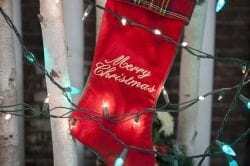 Image showing a red Christmas stocking hanging from a tree with christmas lights shining around it.