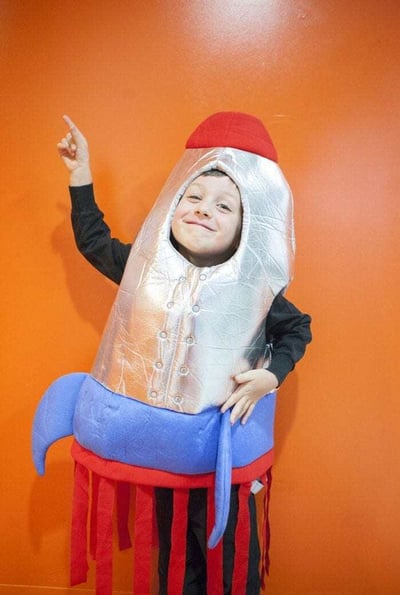 Image showing a young boy wearing a rocketship Halloween costume and pointing upward. Image showing a young boy wearing a rocketship Halloween costume and pointing upward.