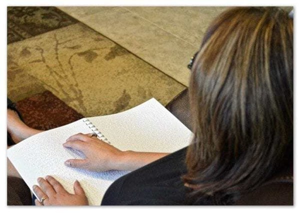 Over-the-shoulder view of a woman reading a braille document. Over-the-shoulder view of a woman reading a braille document.