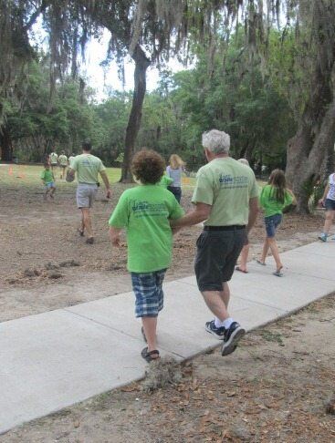 Image of Lou Fioritto (Founder & Co-Owner of Braille Works) walking with his grandson during a company picnic. Lou Fioritto (Co-founder of Braille Works) walking outside with his grandson at a company picnic.