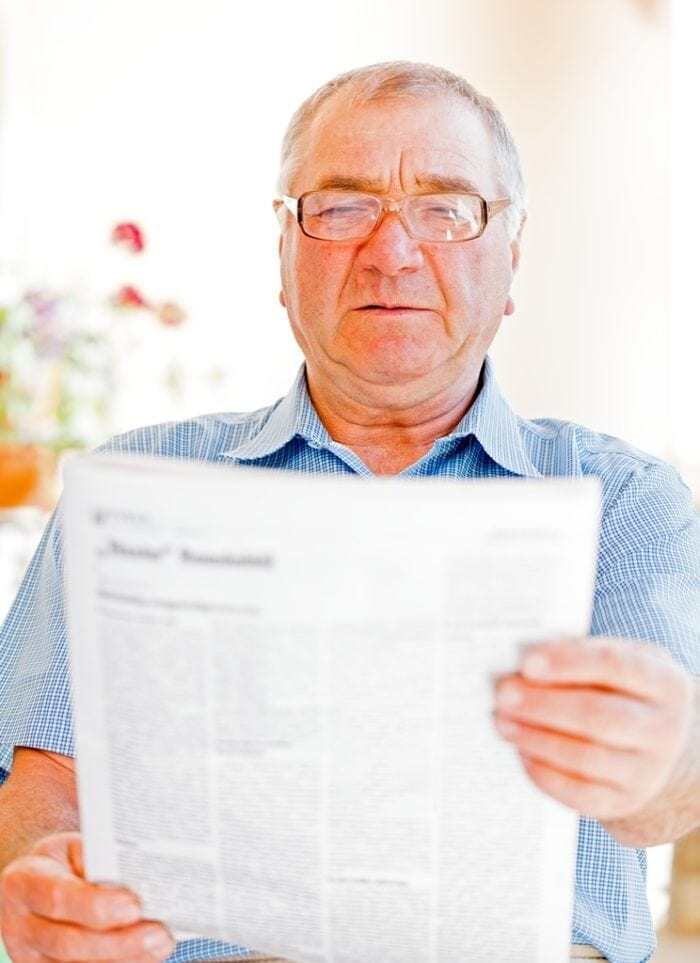 Elderly man reading newspaper on the veranda