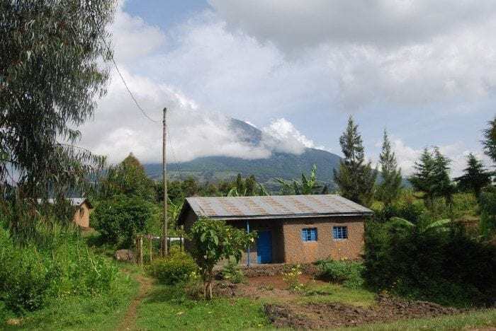 Image showing a typical Rwandan house with the Muhabura Volcano in the distant background.