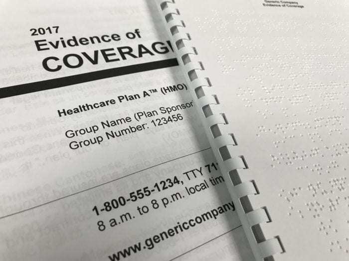close up of a Braille and large print Evidence of Coverage documents.