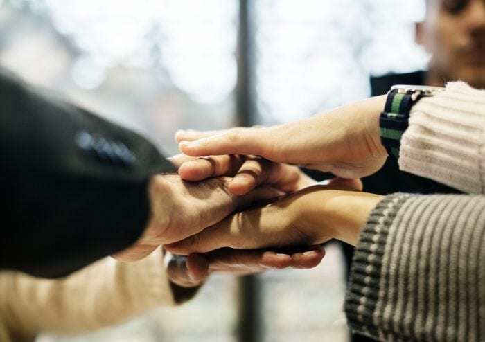 group of people with their hands put in and stacked on top of one another to represent teamwork