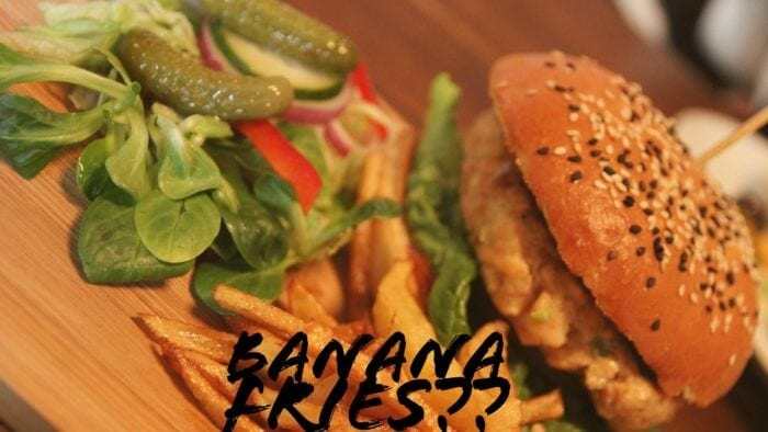 A burger and fries topped with lots of condiments, with the words "Banana Fries??" overlaid on top.