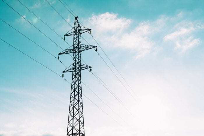 Utility pole with wires running through with a cloudy and blue sky in the background