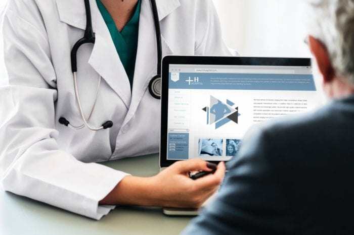 Doctor explaining a healthcare website on a laptop to a patient