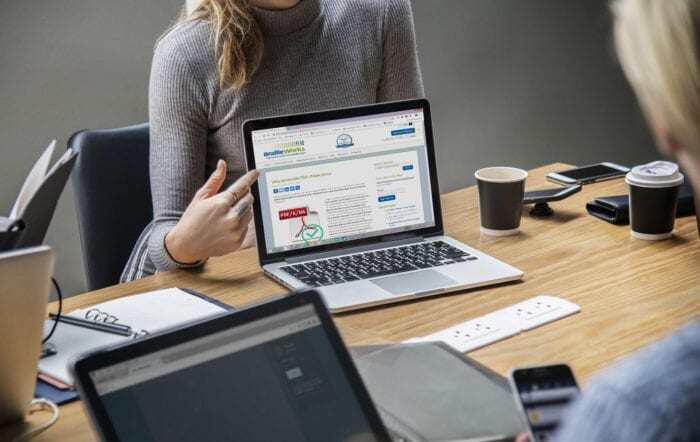 Work meeting with a woman pointing to a laptop screen with Braille Works blog "Why Accessible PDFs Make Sense"