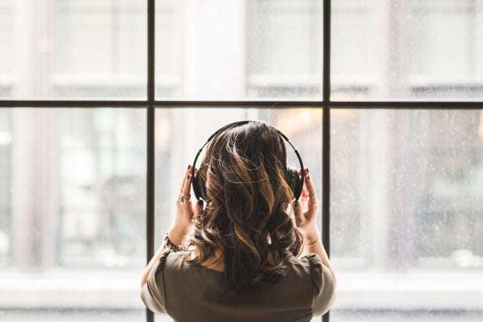 employee stares out of the window while listening to curated music with headphones