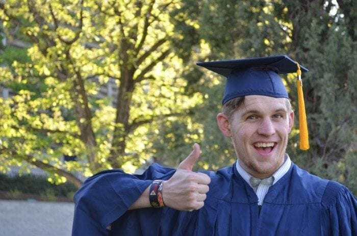 A young man wearing a graduation cap and gown, smiling and giving a thumbs up. A young man wearing a graduation cap and gown, smiling and giving a thumbs up.