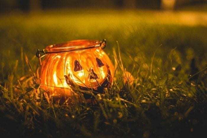 a jack o'lantern candle sits in the grass