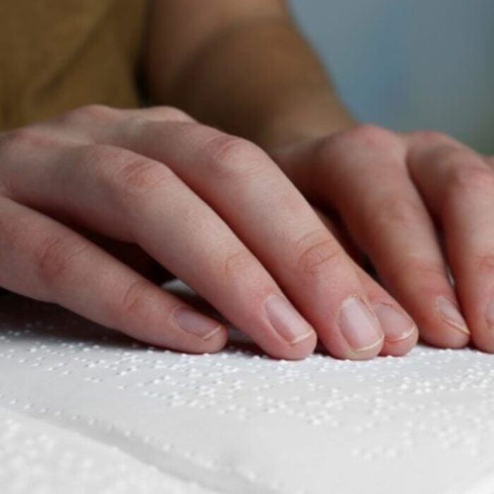 individual using their fingertips to read braille