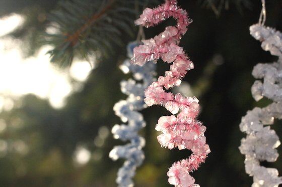 Three crystal pipe cleaner shapes hanging from a Christmas tree.