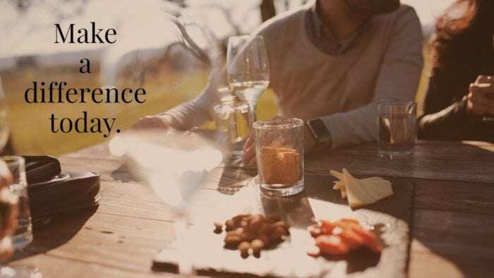 A table setting with food and drinks, with a person leaning out of view. The words "make a difference today," are overlaid.