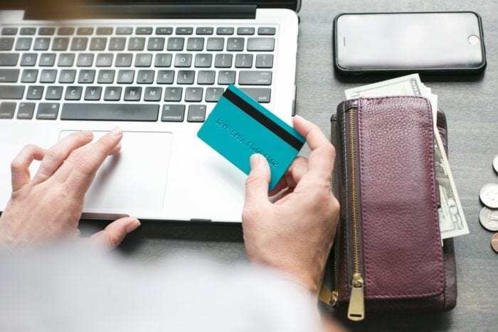 Woman sitting at a desk using her laptop and debit card.