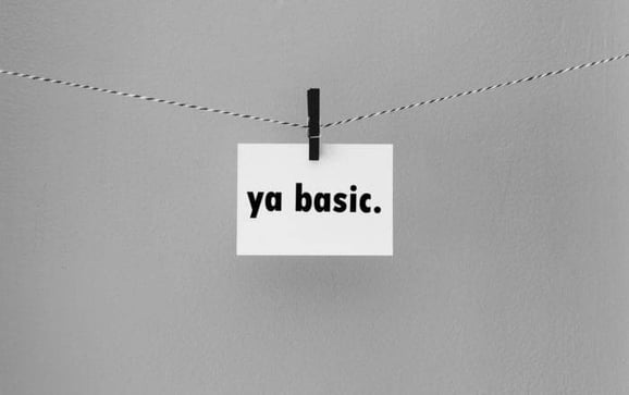 Note card with the text "ya basic." held on a string by a clothespin