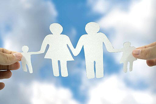 paper cutout of a family held up against the sky